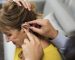 A doctor inserting hearing aid to a patient's ear